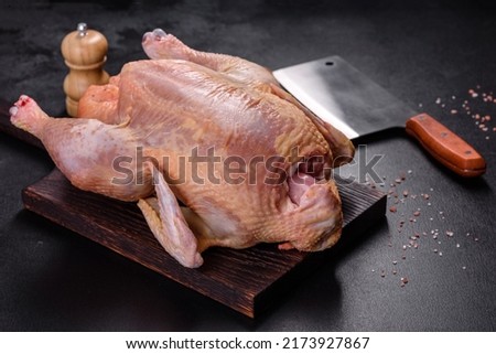 Raw turkey or chicken with salt, spices and herbs on a wooden cutting board against a dark concrete background. Preparing a festive table