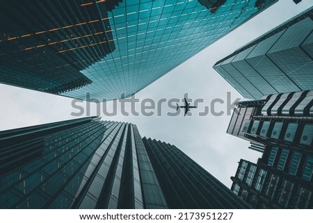 Look up shot of plane flying over buildings in London Liverpool street.  Royalty-Free Stock Photo #2173951227