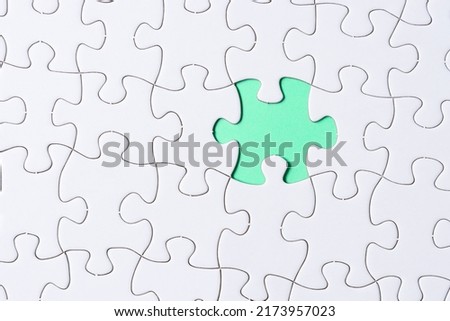 Piece of jigsaw puzzle on green paper. Flat lay, Directly above.