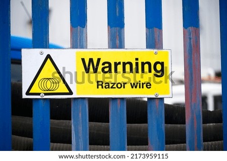 Razor wire warning sign on security fence at construction site