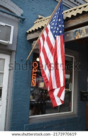 American flag by an open sign on a storefront