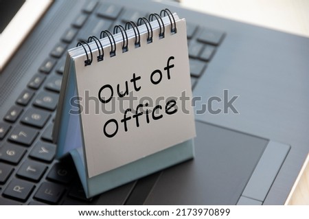 Out of office text on calendar desk on top of a laptop. Business concept