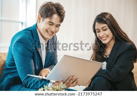Business couple sitting together with laptop and checking work on sofa in the office.