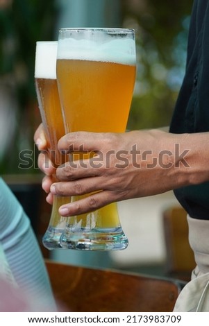 Pint of chilled beer being served in weizen glass at a pub.                             