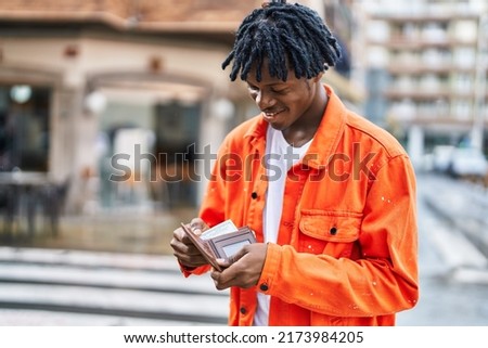 African american man smiling confident holding wallet with dollars at street Royalty-Free Stock Photo #2173984205