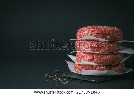 Raw ground beef burger patties separated by parchment paper on a black background Royalty-Free Stock Photo #2173991843