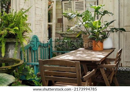 outdoor vintage home garden decoration. Wooden table and chair for lunch outside in the garden with warm sunlight at beautiful morning in summer.