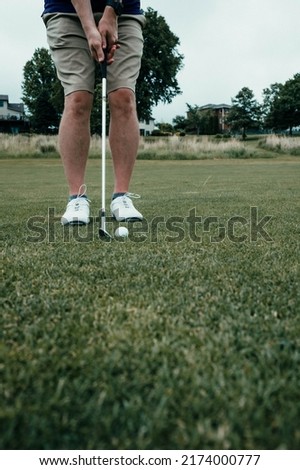A vertical shot of a person playing golf on a field