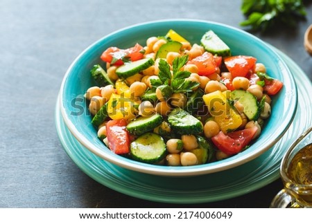 Chickpea salad with tomatoes, cucumber, parsley, onions in a plate, selective focus. Healthy vegetarian food, oriental and Mediterranean cuisine. Chick peas salad Royalty-Free Stock Photo #2174006049