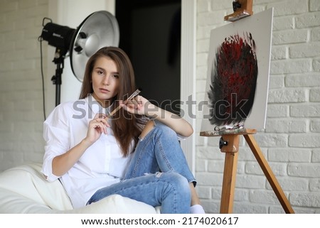 Beautiful girl artist at work in a creative white studio