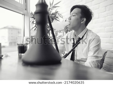 A young Asian businessman is waiting for a partner in a cafe. A Korean young man talking on the phone in a cafe.
