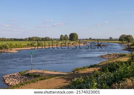 The Dutch river IJssel flows peacefully through the typical Dutch landscape. Royalty-Free Stock Photo #2174023001