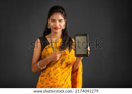 Young beautiful girl showing a blank screen of a smartphone or mobile or tablet phone