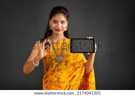 Young beautiful girl showing a blank screen of a smartphone or mobile or tablet phone