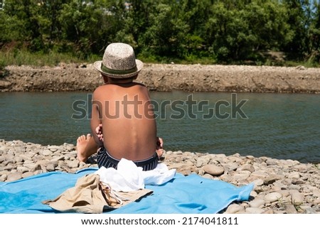the boy sits and looks at the river