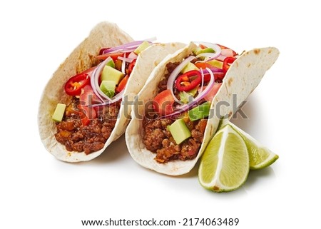 Two tacos with ground beef and lime on white background