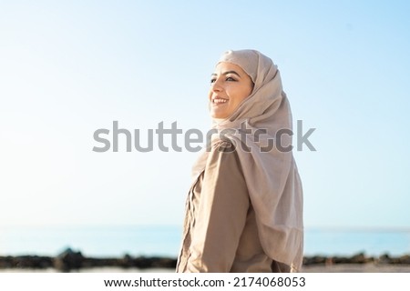 Muslim and modern woman smiling on the beach with hope and happiness