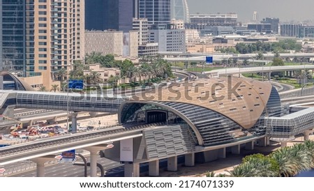 Futuristic building of Dubai metro station and luxury skyscrapers behind in Dubai Marina aerial timelapse. Traffic on Sheikh Zayed road highway near media city, United Arab Emirates