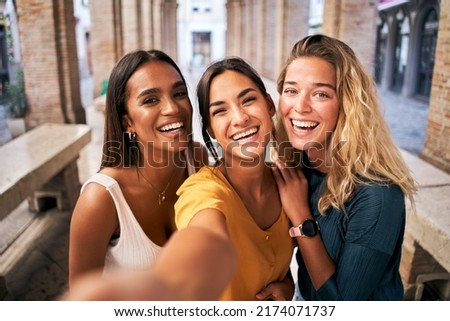 Three young smiling 20s young girls in summer clothes. Women taking selfie self portrait photos on smartphone.