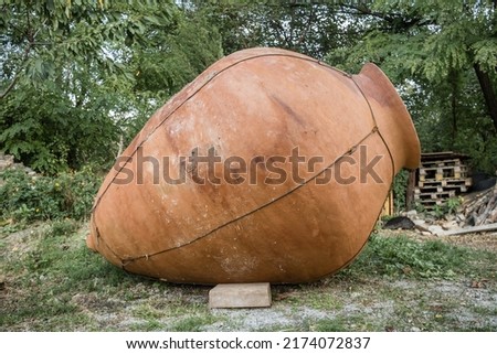 Big kvevri in garden in front of a stone wall, Georgia. Qvevri is a large earthenware vessel originally from Georgia, Caucasus. It is used for the fermentation and storage of wine Royalty-Free Stock Photo #2174072837