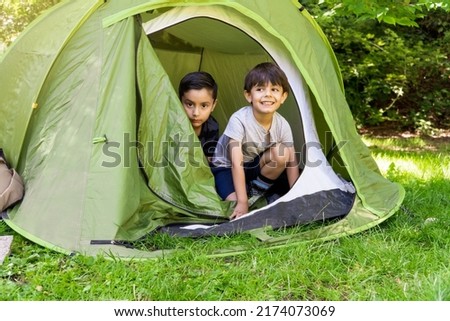 multiethnic latin and caucasian children learning to pitch a tent on a summercamp. Vacation concept Royalty-Free Stock Photo #2174073069