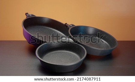 Concept of kitchen utensils, close up of new set of frying pans lying on the table. Action. New modern non stick pans. Royalty-Free Stock Photo #2174087911