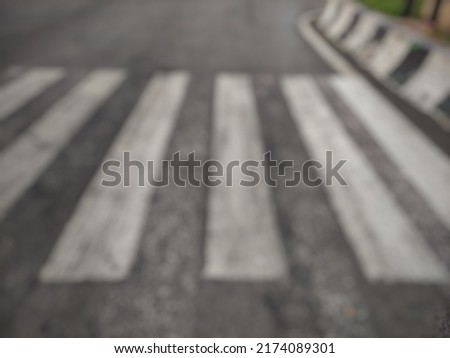 defocused abstract background of zebra cross with white color starting to fade at the highway intersection. 