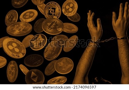 Hands in handcuffs and cryptocurrencies over dark background. Crypto crime concept. 
