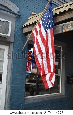 American flag by an open sign on a storefront