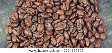 Heap of dark roasted coffee grains on concrete structure