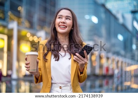 Urban modern lifestyle fashion portrait of asian young female stylish casual Asia woman walking 
 with coffee cup and smartphone connection on the street, wearing cute trendy outfit after raining Royalty-Free Stock Photo #2174138939
