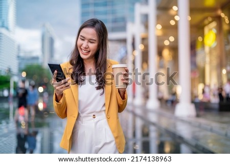 Urban modern lifestyle fashion portrait of asian young female stylish casual Asia woman walking 
with coffee cup and smartphone connection on the street, wearing cute trendy outfit after raining Royalty-Free Stock Photo #2174138963