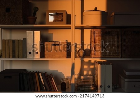 Sunlight shadow on storage shelves with books, boxes. Aesthetic home office interior design