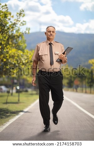 Full length portrait of a security guard walking on a pedestiran lane