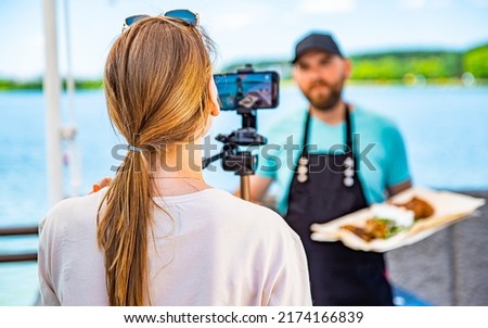 man chef gives an interview for a video blogger. videographer is filming the cook's story about cooking. outdoor