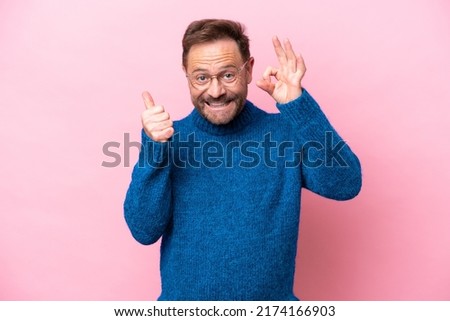 Middle age caucasian man isolated on pink background showing ok sign and thumb up gesture