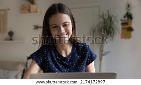 Positive happy young freelancer woman using laptop at home, chatting online, making video call, laughing, watching webinar, lecture, taking learning course. Front view, banner shot