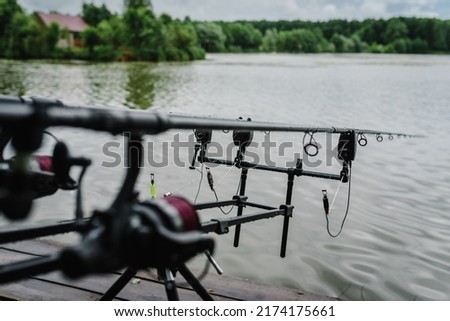 Spinning. Feeder fishing with reel. Rod pod. Fishing rods for pike, perch, carp on the pond. Angler with fishing technique. Fishing in rainy weather, rain. World Fisherman's Day, photo for article.