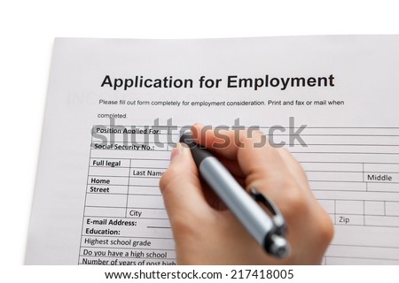 Closeup of a male hand holding a pen completing a job application form in a career and employment concept Royalty-Free Stock Photo #217418005