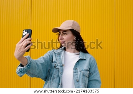portrait of a young woman in headphones taking a selfie or recording a video on the phone