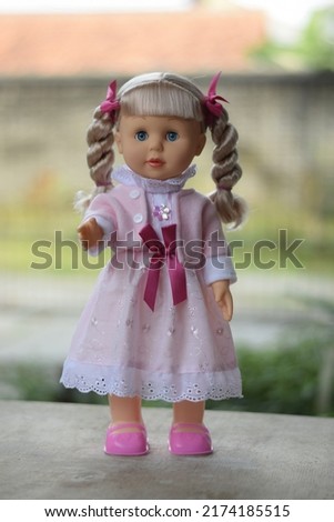 girl doll in pink dress standing on blur background