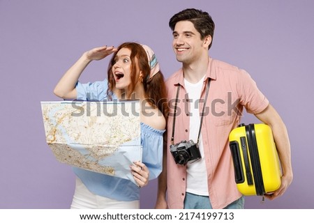 Two fun traveler tourist woman man couple in shirt hold suitcase paper map look far away distance isolated on purple background Passenger travel abroad on weekends getaway Air flight journey concept