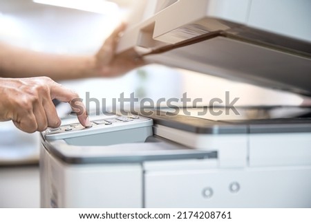 Photocopier printer, Close up hand office man press copy button on panel to using the copier or photocopy machine for scanning document or printing paper or Xerox a sheet. Royalty-Free Stock Photo #2174208761