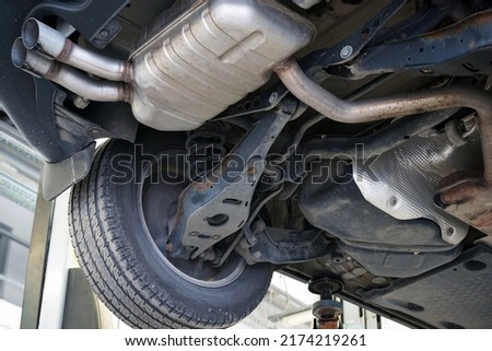 Modern car in a car service on a lift. Suspension elements and exhaust system. Auto parts and car service. Selected focus. Royalty-Free Stock Photo #2174219261