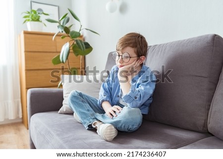Kid bored face looking deep in thought,Lonely boy with thinking face sitting alone on sofa,Upset schoolboy child with unhappy or sad face,Spoiled children,Mental health