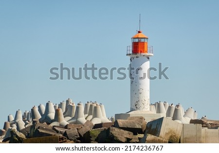 Lighthouse, breakwaters close-up. Baltic sea shore. Clear blue sky, sunny summer day. Nature, environment, ecology, ecotourism, hiking, exploring, navigation themes. Latvia Royalty-Free Stock Photo #2174236767