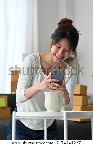 Asian woman business owner taking photo to vase with smart phone for post to selling online on the internet, Start up small business owner work at home concept.