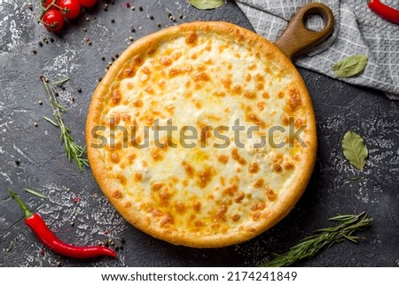 Cheese pizza on board on dark stone table top view