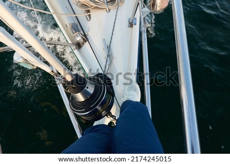Man in a blue jeans and white boots standing on deck of a sloop rigged yacht. Baltic sea. Healthy lifestyle, sport, recreation, cruise, vacation, regatta, sailing lessons, leisure activity, wanderlust Royalty-Free Stock Photo #2174245015
