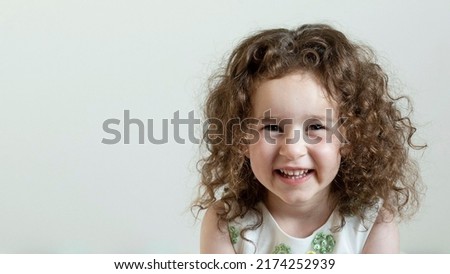 Portrait of a cute positive girl with curly hair. Daylight. White background. The concept of children, childhood, lice, healthy child.
